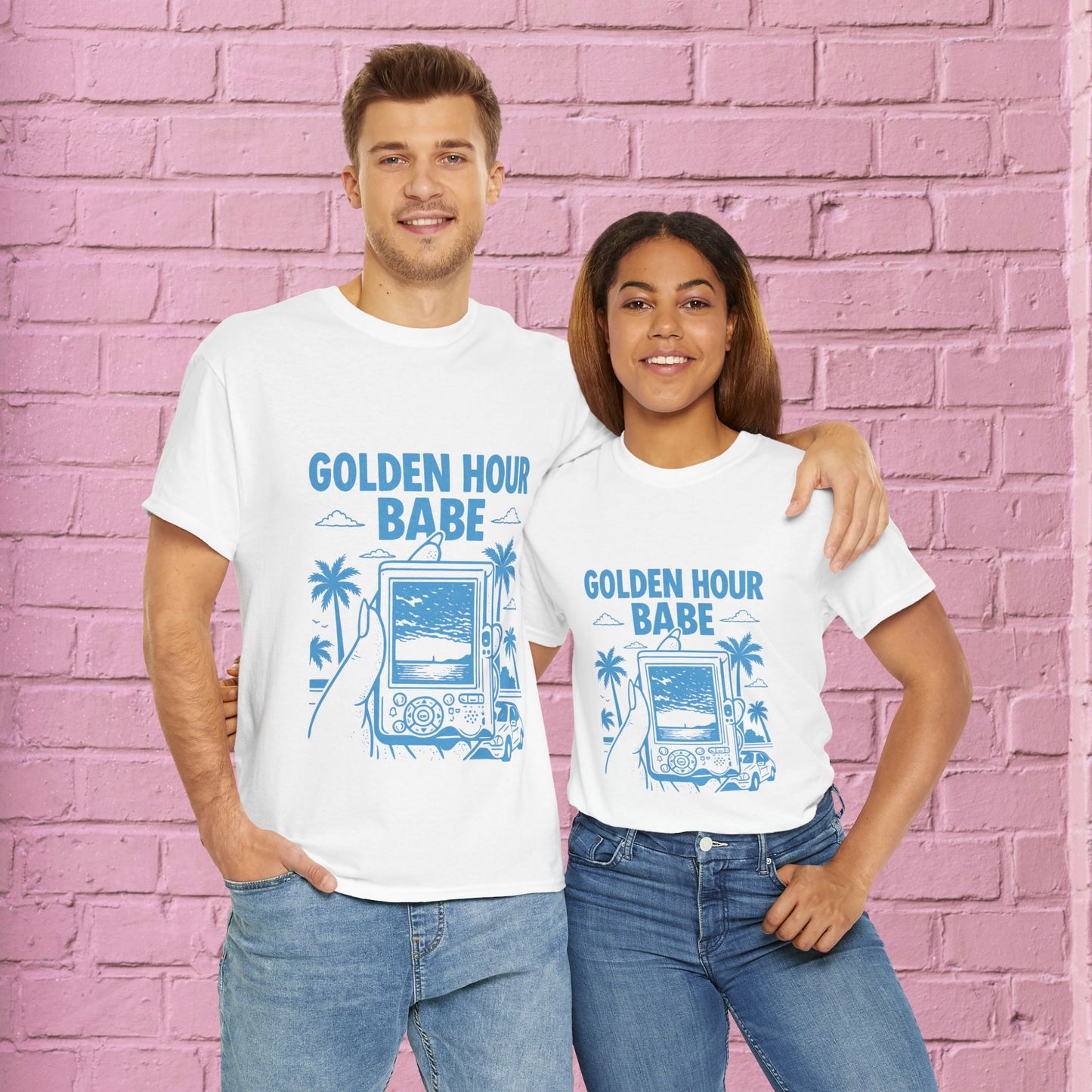 Two people wearing 'Golden Hour Babe' t-shirts against a pink brick wall.