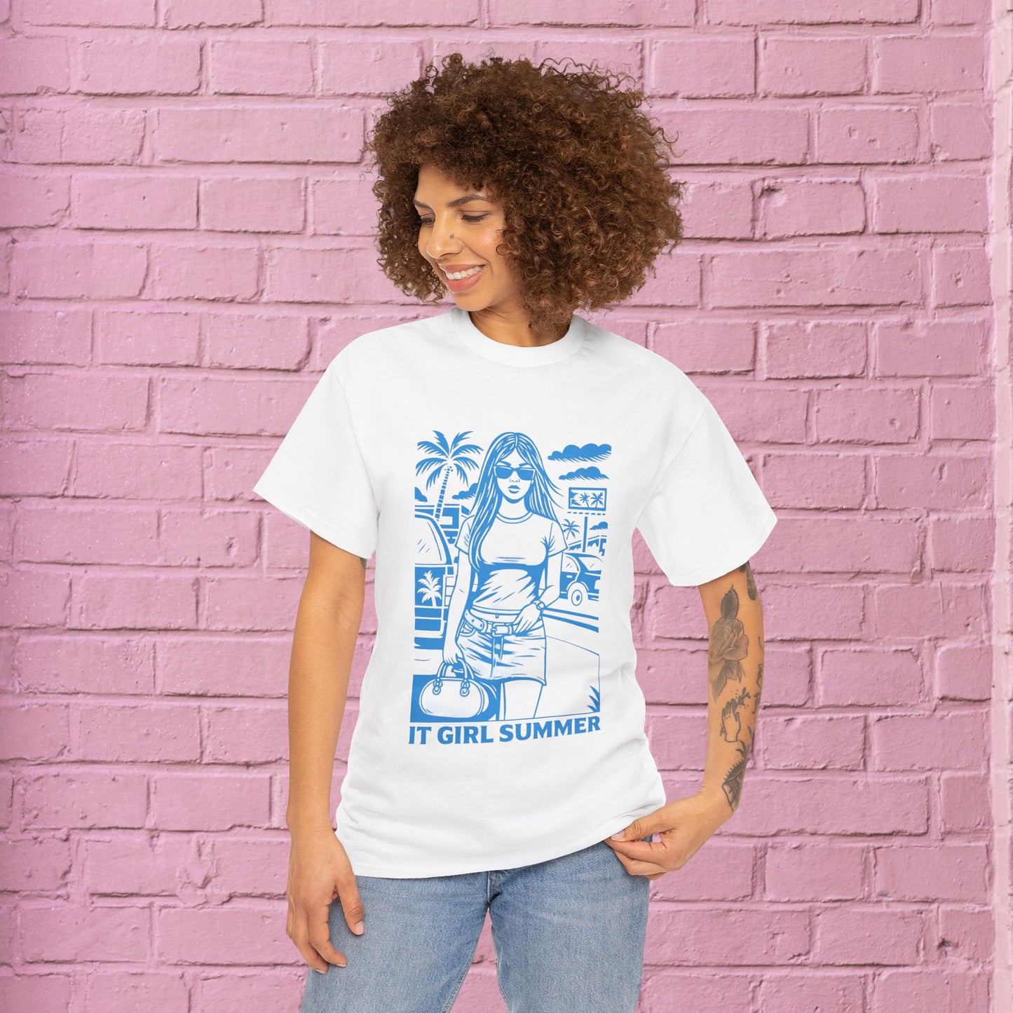 Woman wearing a white t-shirt with blue graphic design against a pink brick wall