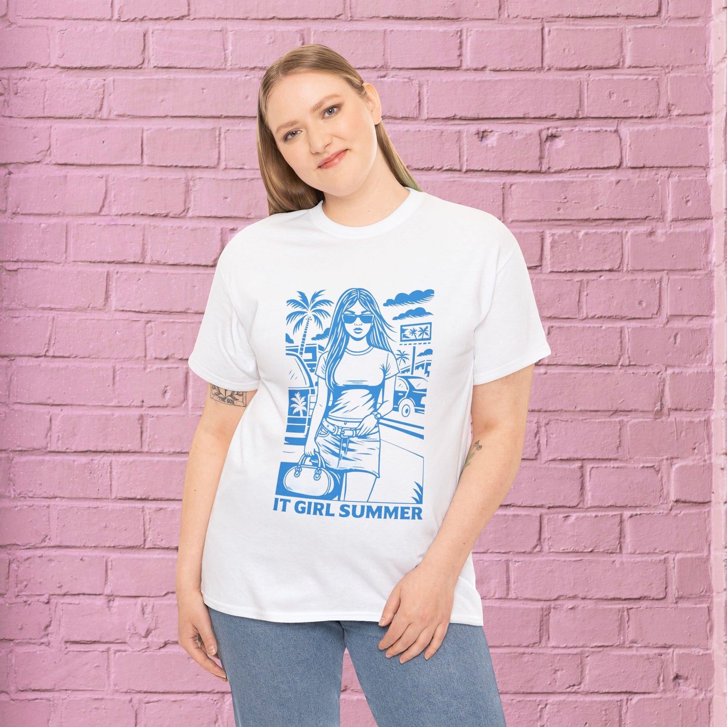 Person wearing a white t-shirt with blue graphic design against a pink brick wall