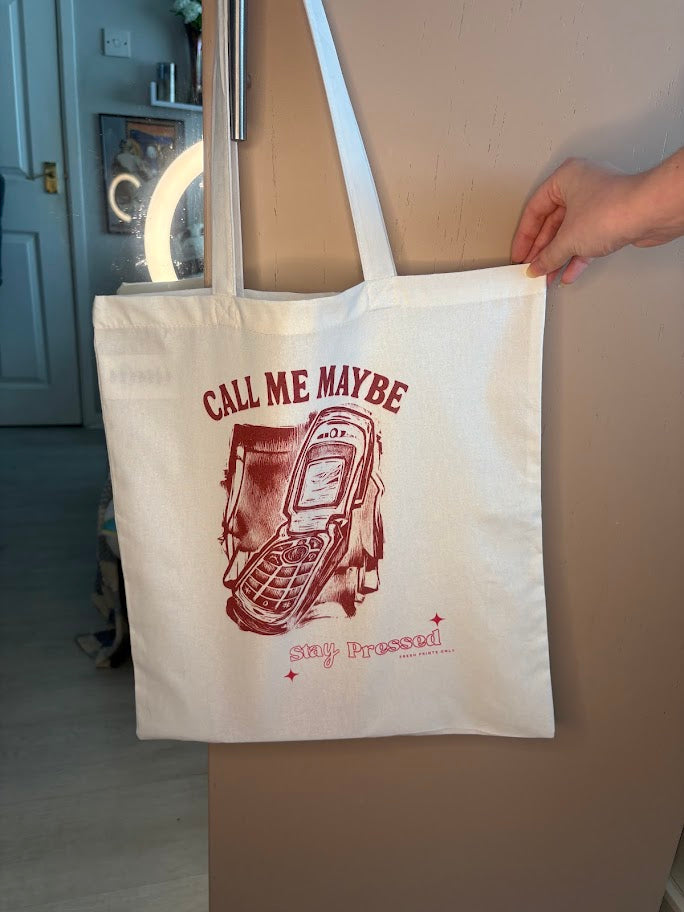 Tote bag with 'Call Me Maybe' design held by a person indoors.