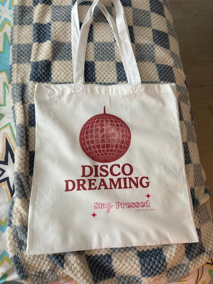 Tote bag with 'Disco Dreaming Stay Pressed' text on a checkered fabric background
