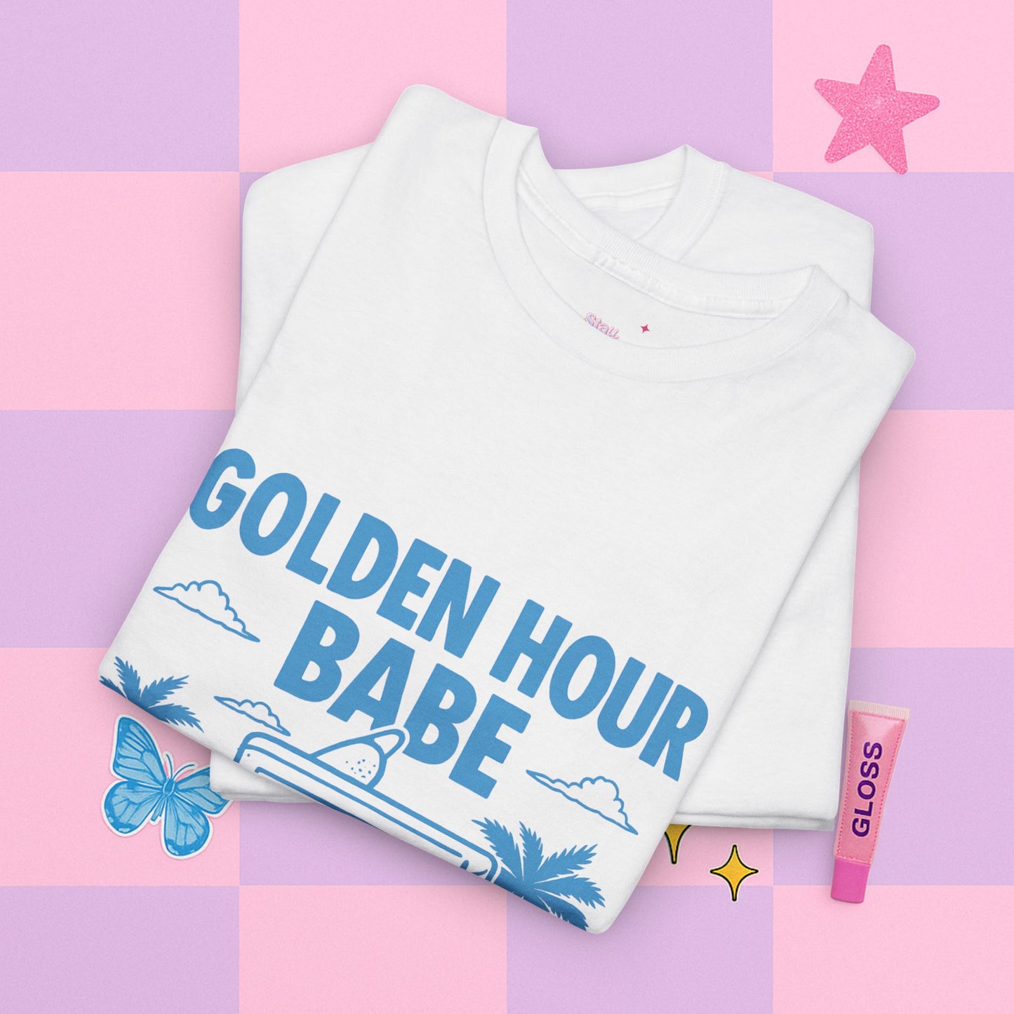 Folded white t-shirt with 'GOLDEN HOUR BABE' text on a colorful background