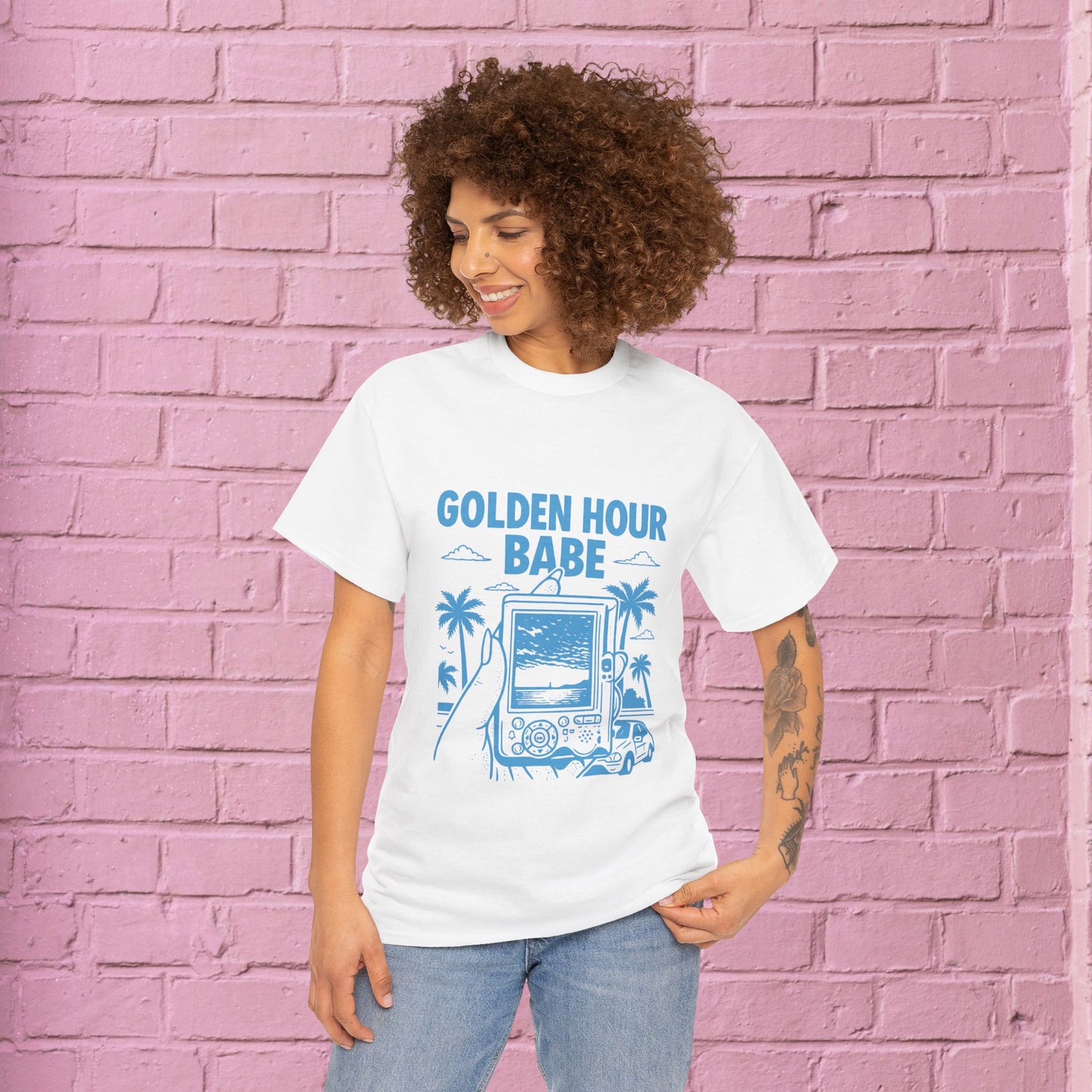 Woman wearing a 'Golden Hour Babe' t-shirt against a pink brick wall