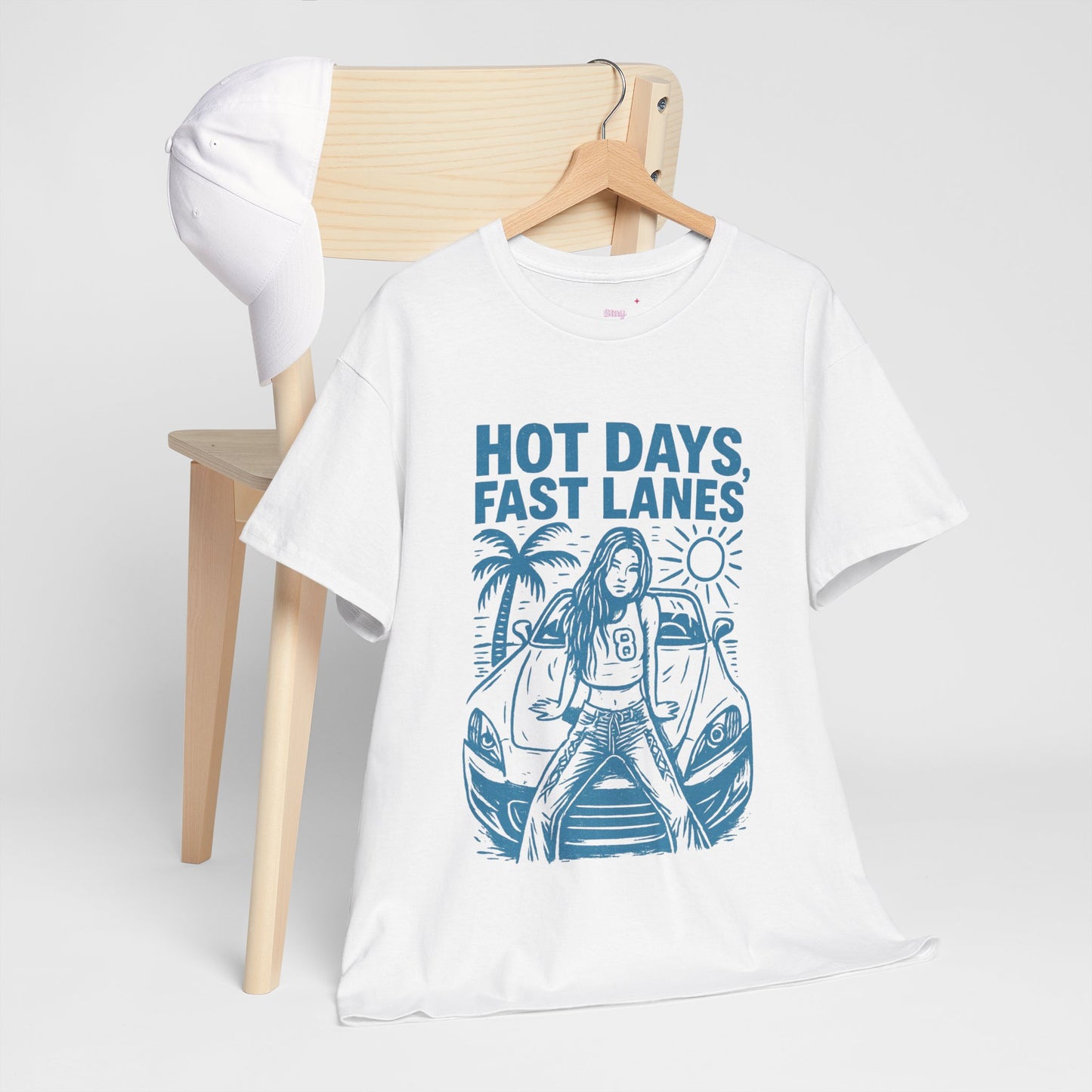 White t-shirt with blue graphic design and text on a wooden chair against a white background