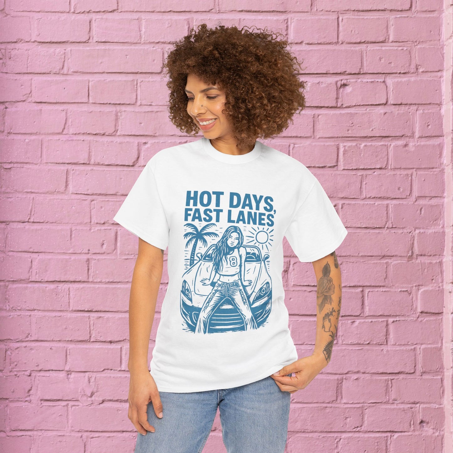 Person wearing a white t-shirt with blue graphic and text against a pink brick wall