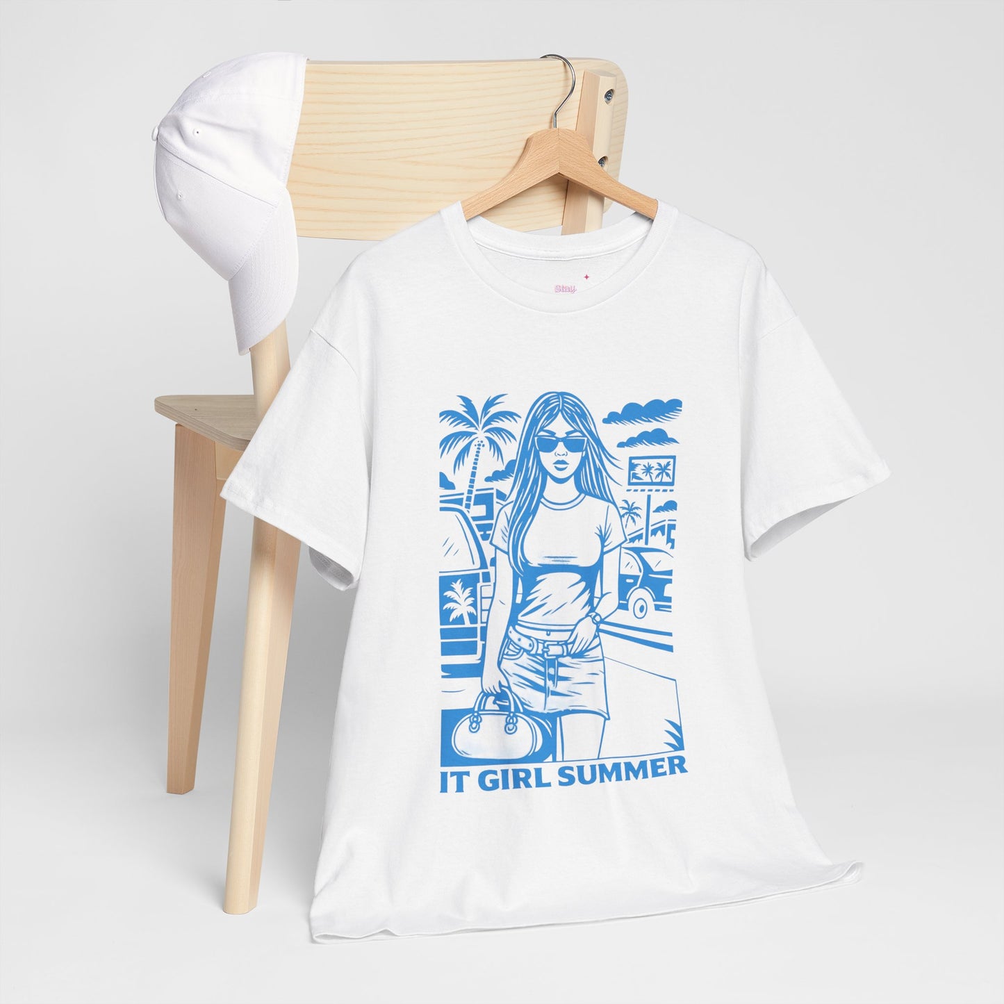 White t-shirt with blue graphic design on a wooden chair against a white background