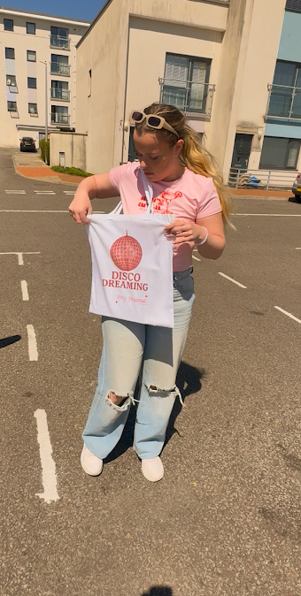Person holding a tote bag with text on a street