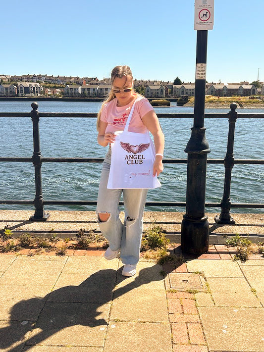 Person holding a sign with text by a waterfront on a sunny day